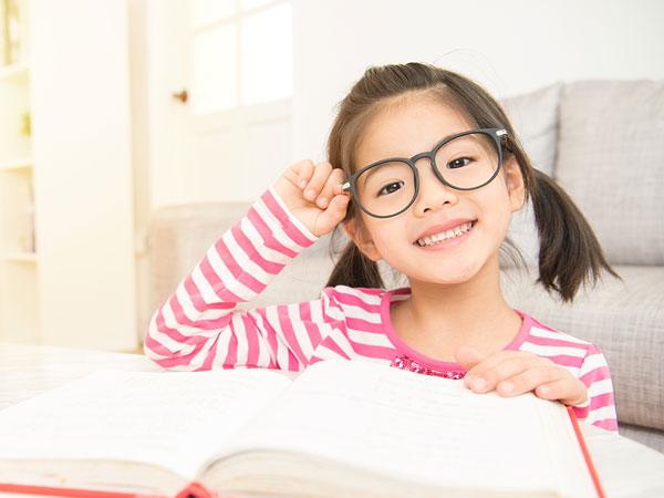 Manhattan Bridge Orthodontics little girl with glasses smiling and reading