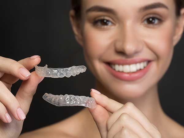 Manhattan Bridge Orthodontics Smiling Lady holding Clear Retainers