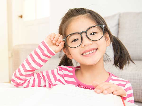 Manhattan Bridge Orthodontics Little Girl with Glasses Smiling and Reading